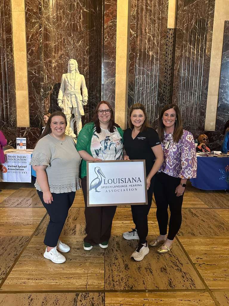 Four LSHA members holding the LSHA pelican sign in the Louisiana State Capitol rotunda.